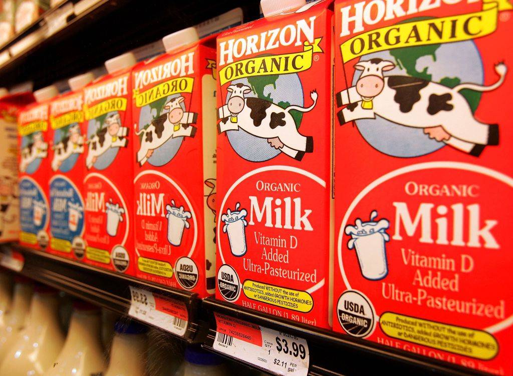 Cartons of organic milk sit on a cooler shelf