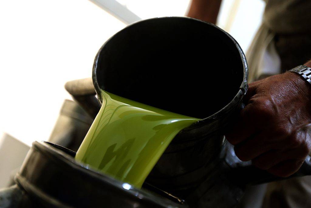 A worker pours fresh olive oil into a container