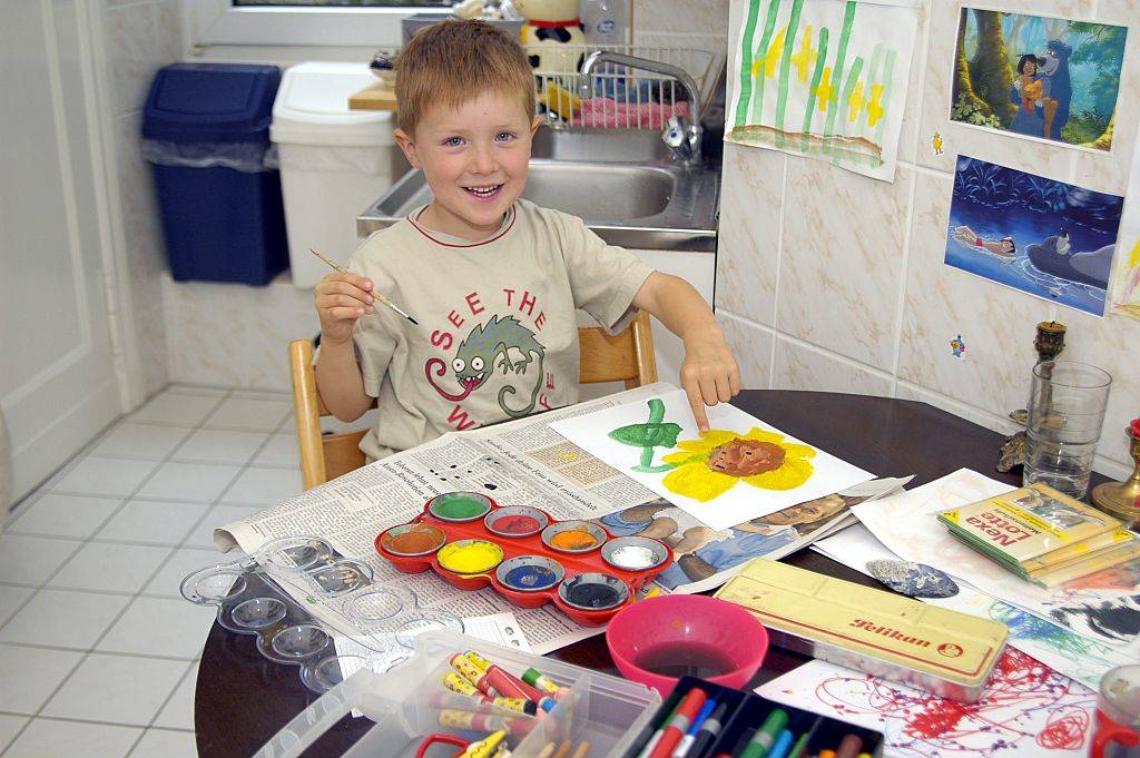 little boy painting in a kitchen