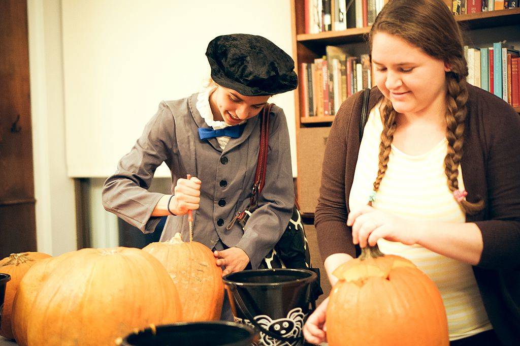 two young women carving pumpkins