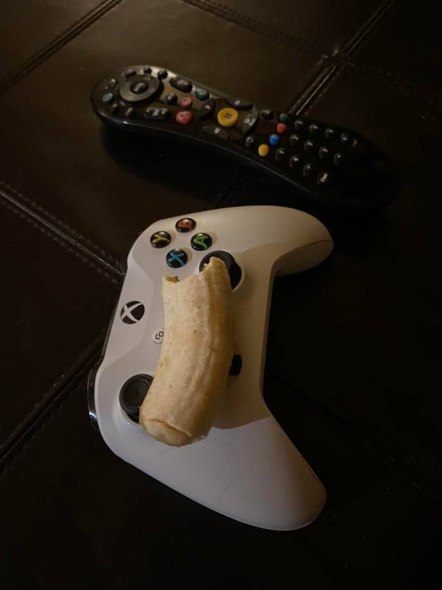 Unpeeled banana resting on xbox gaming controller