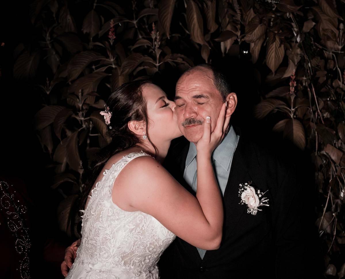 A bride kisses her father on the cheek on her wedding day.