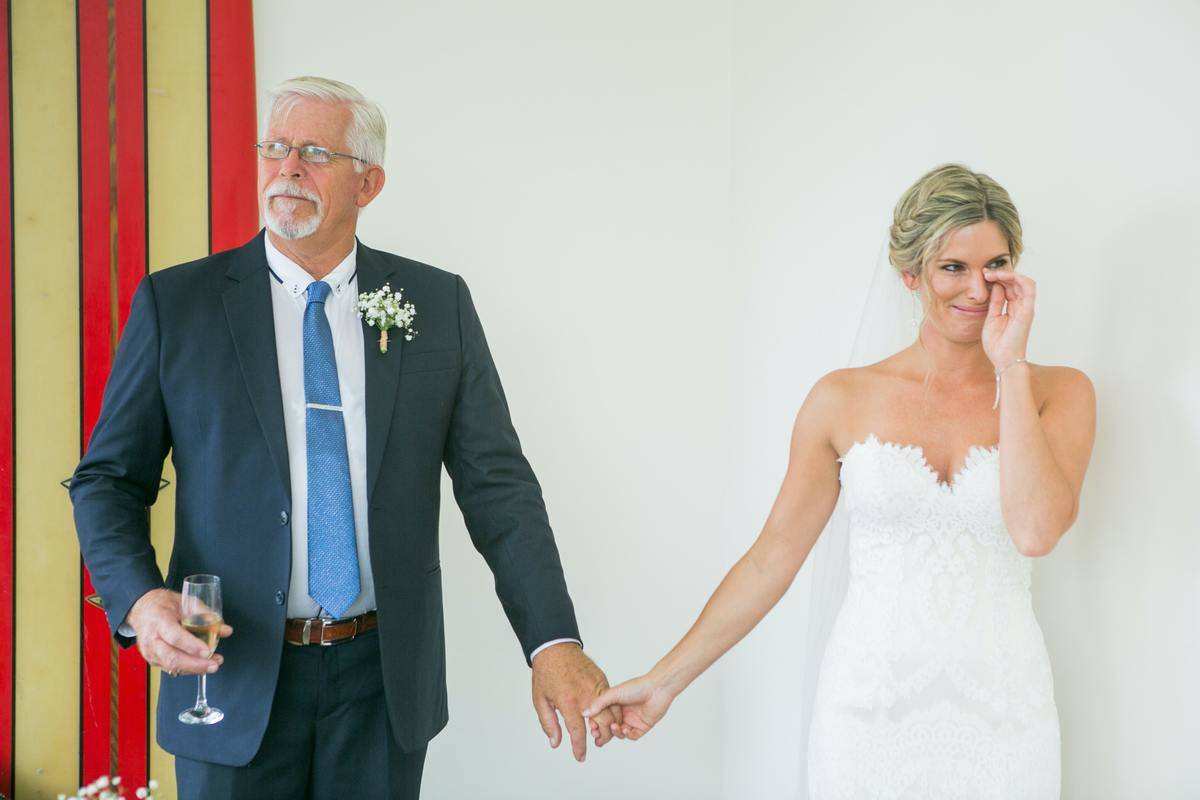 A bride holds her father's hand during a wedding reception.