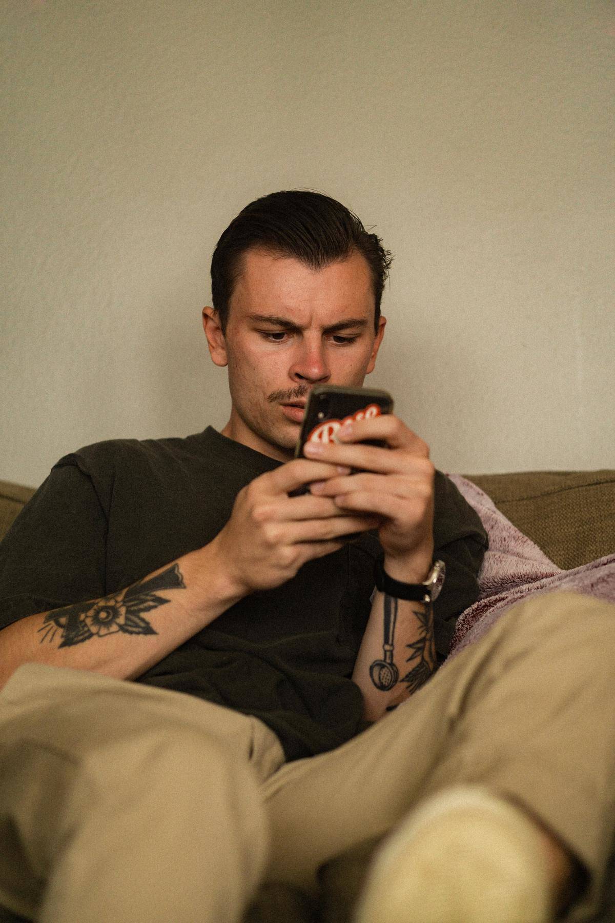 Man sitting on couch looking at cell phone 