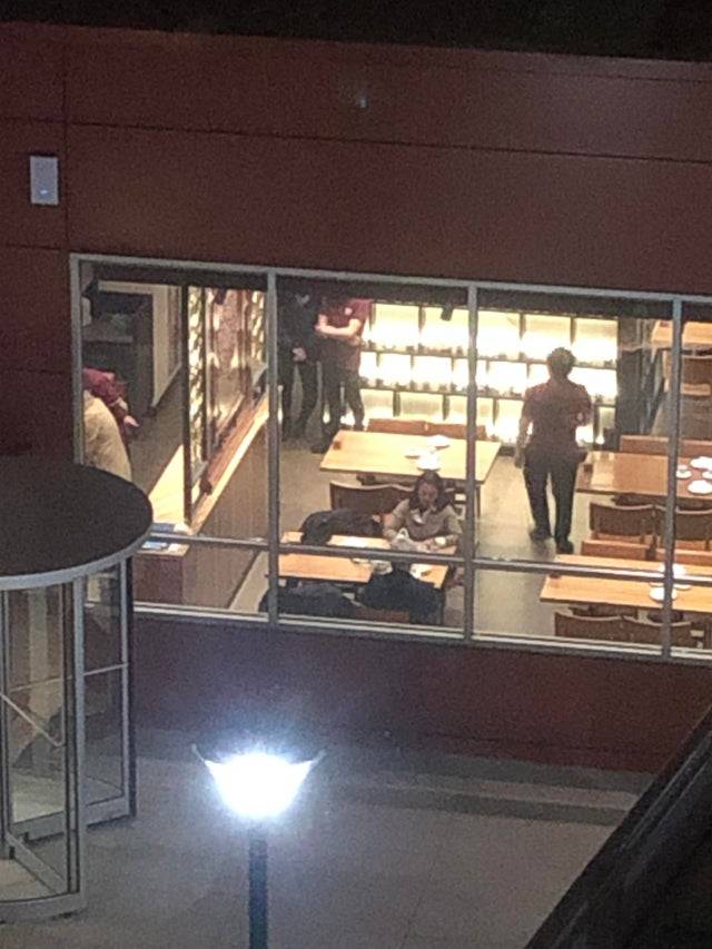 Couple sits at a table past closing while restaurant staff stand nearby. 