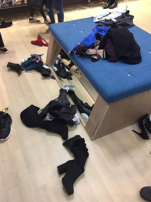 Shoes and clothing are strewn all over the floor at a retail store.