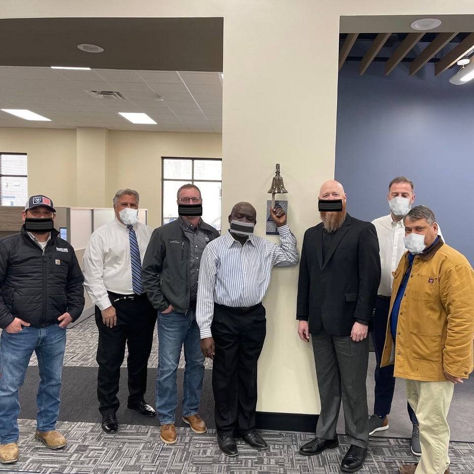 A group of men stand for a group photo and have masks Photoshopped onto their faces.