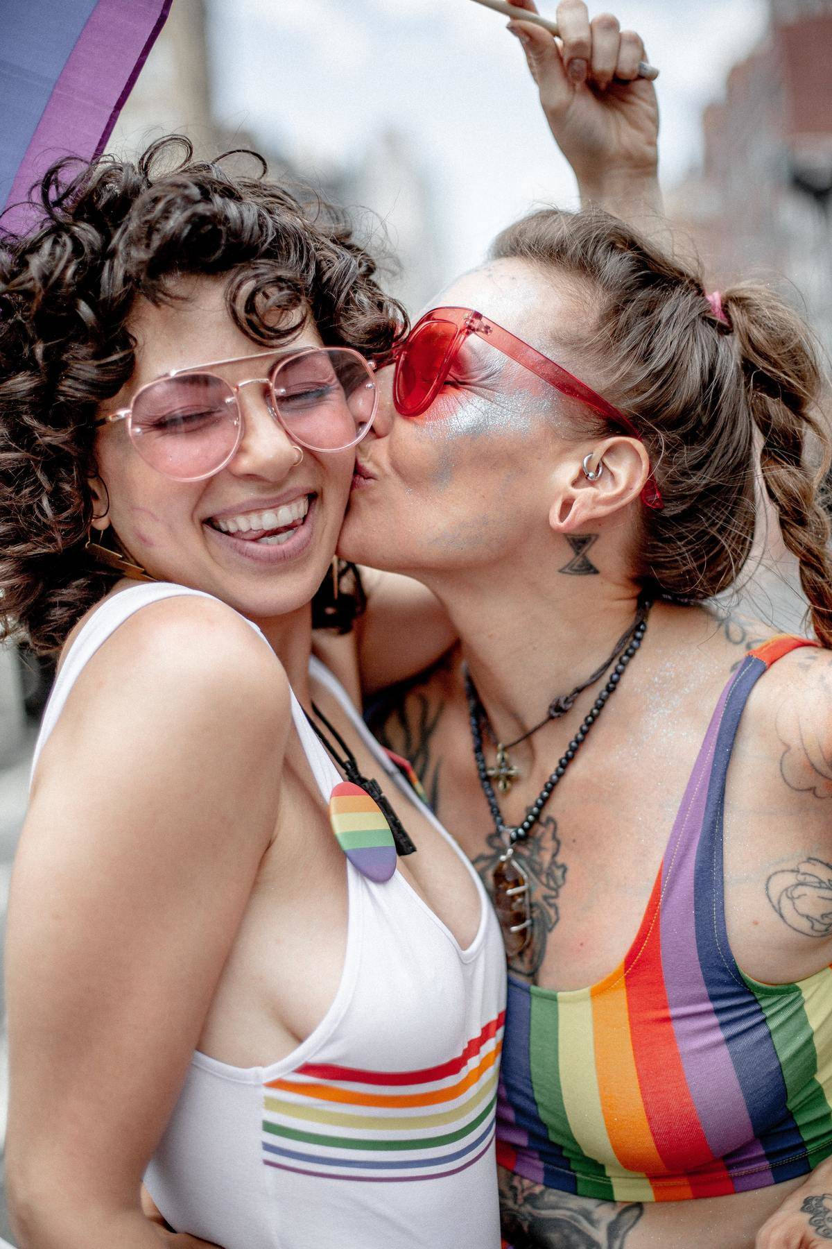 A woman kisses another woman on the cheek during a gay pride parade.