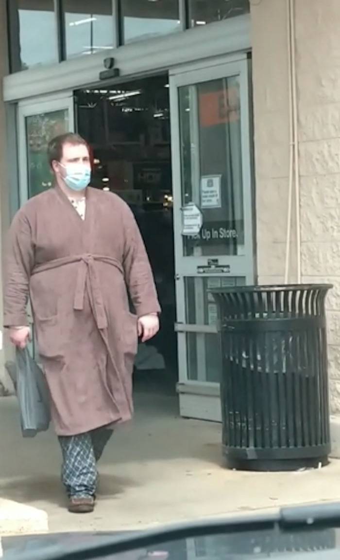 A man walks out of a Home Depot wearing a robe and PJ pants.