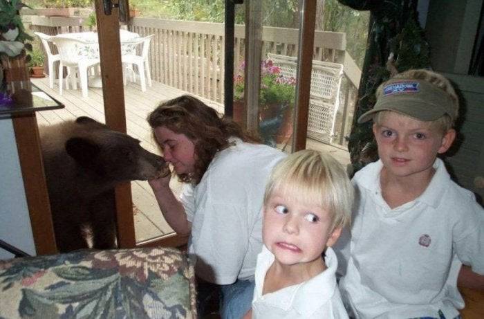 Scared kids and woman petting a wild bear on their back deck.