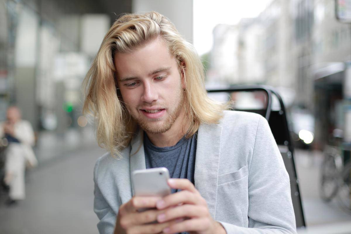Man with long hair smiles at cell phone