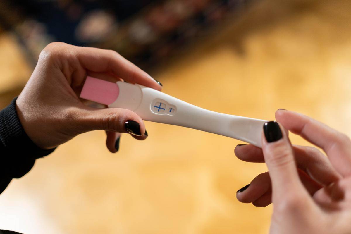 A woman holds a positive pregnancy test.
