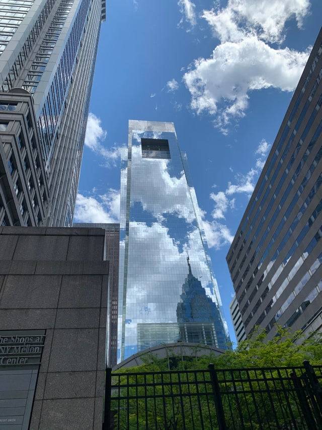 Building with reflective mirror glass blends into the sky on a sunny day
