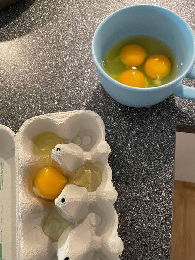 A person makes a bowl of scrambled eggs but cracks one of the eggs into the carton and not the bowl. 