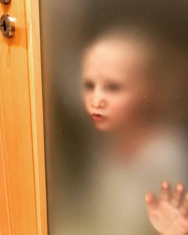 Toddler peering through frosted glass