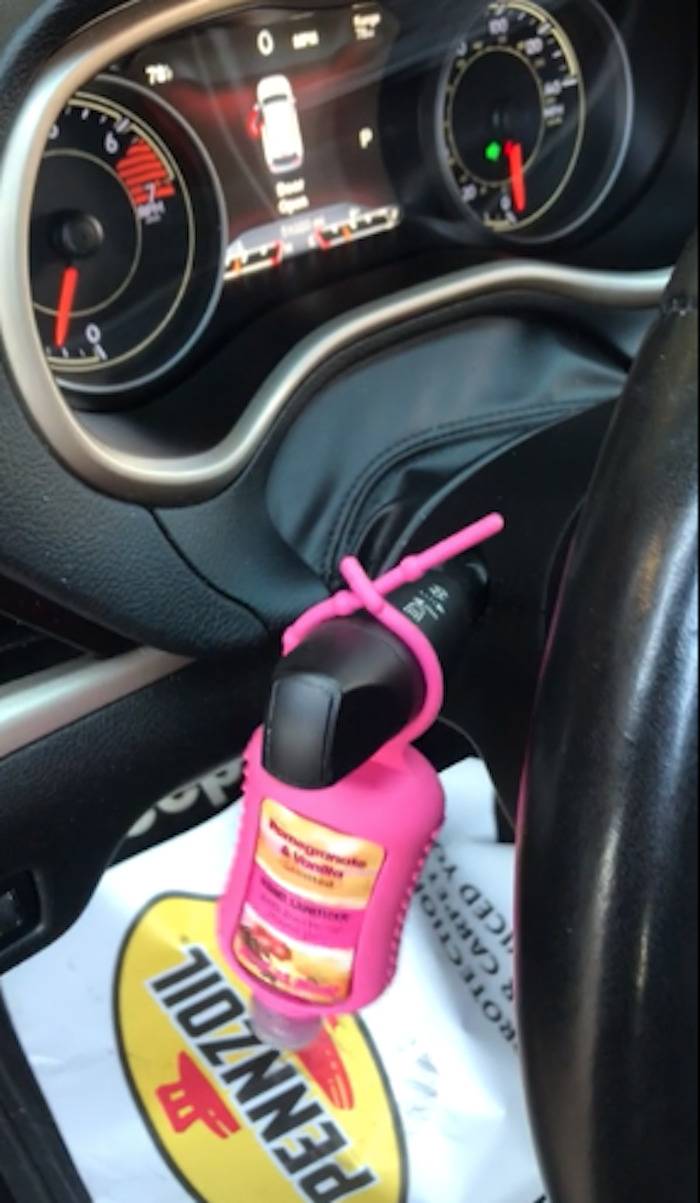 A hand sanitizer dispenser hanging from a car's turn signal.