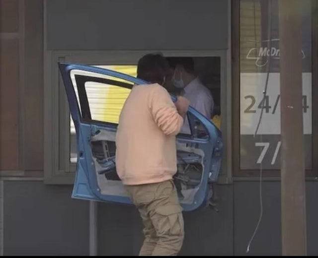 Man holding a car door and walking through a drive-thru