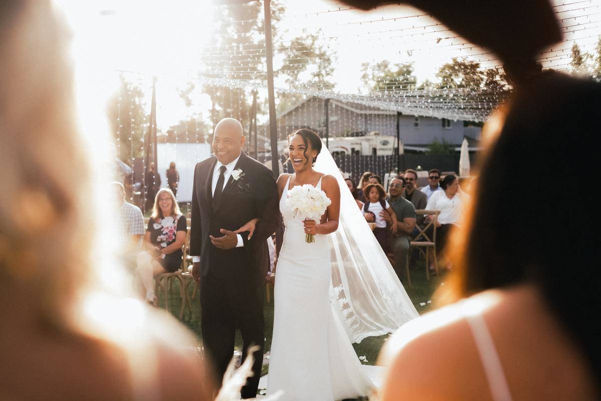 A father walks his father down the aisle on her wedding day.