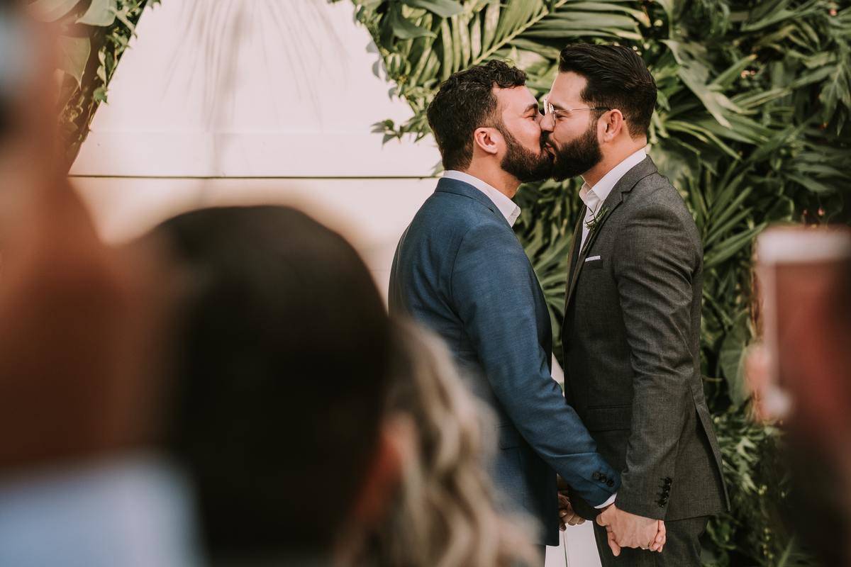 Two grooms kiss at the altar on their wedding day.