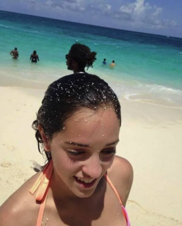 Woman at the beach and woman walking behind her looks like a ponytail