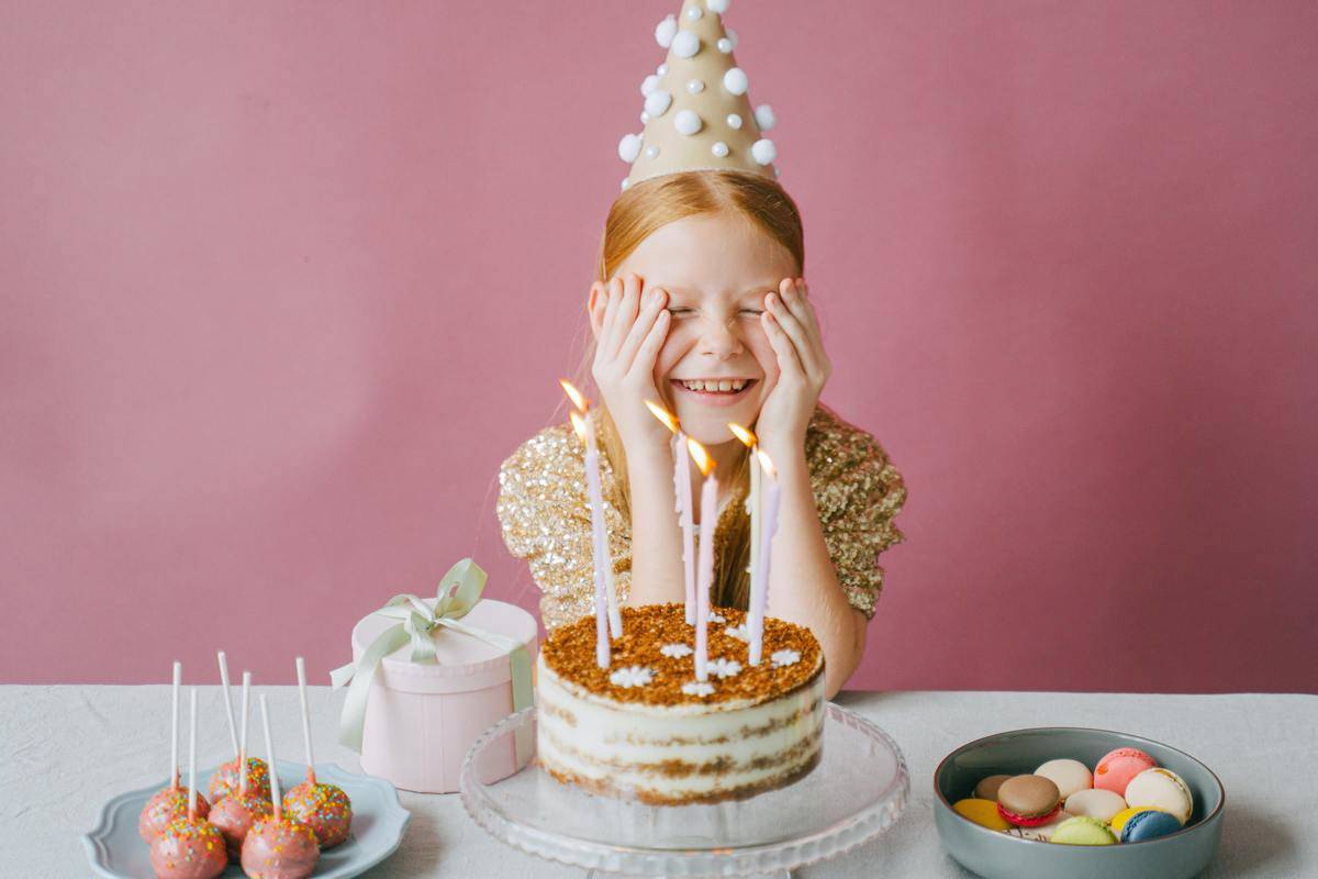 A girl sits in front of her birthday cake with lit candles