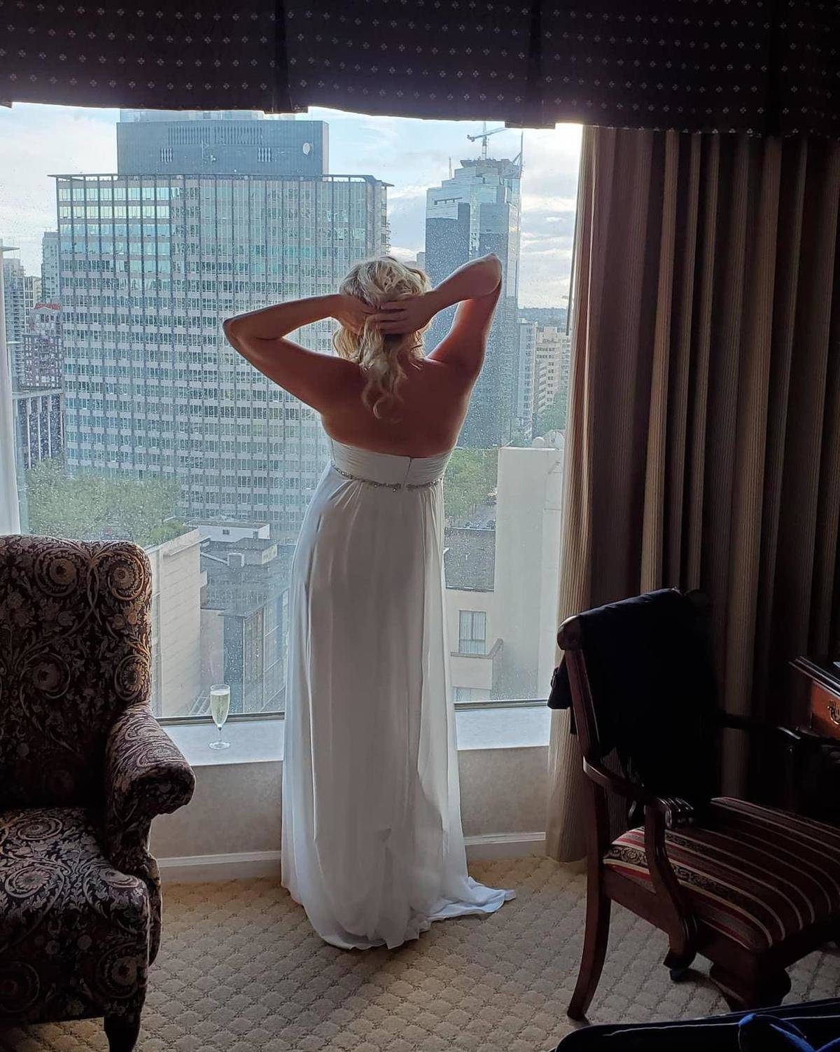 Woman in white dress looking out a window