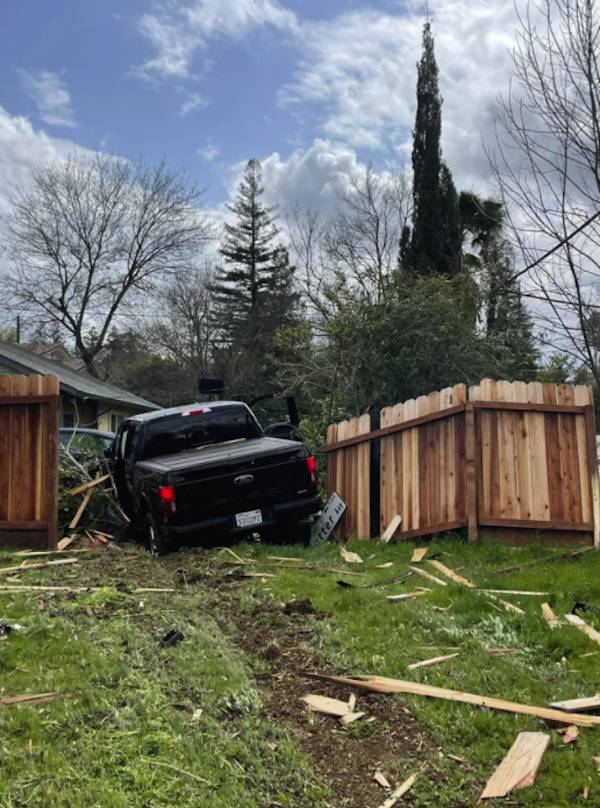 Black truck breaking through a wooden fence. 