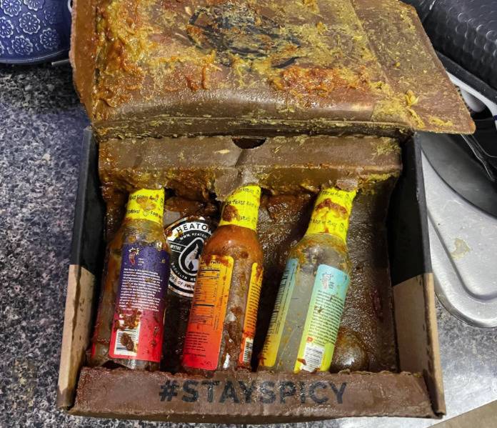 Broken bottles of hot sauce in a wet box. 