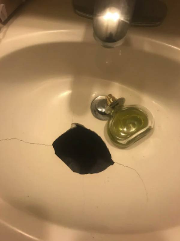 Perfume bottle in a broken sink.