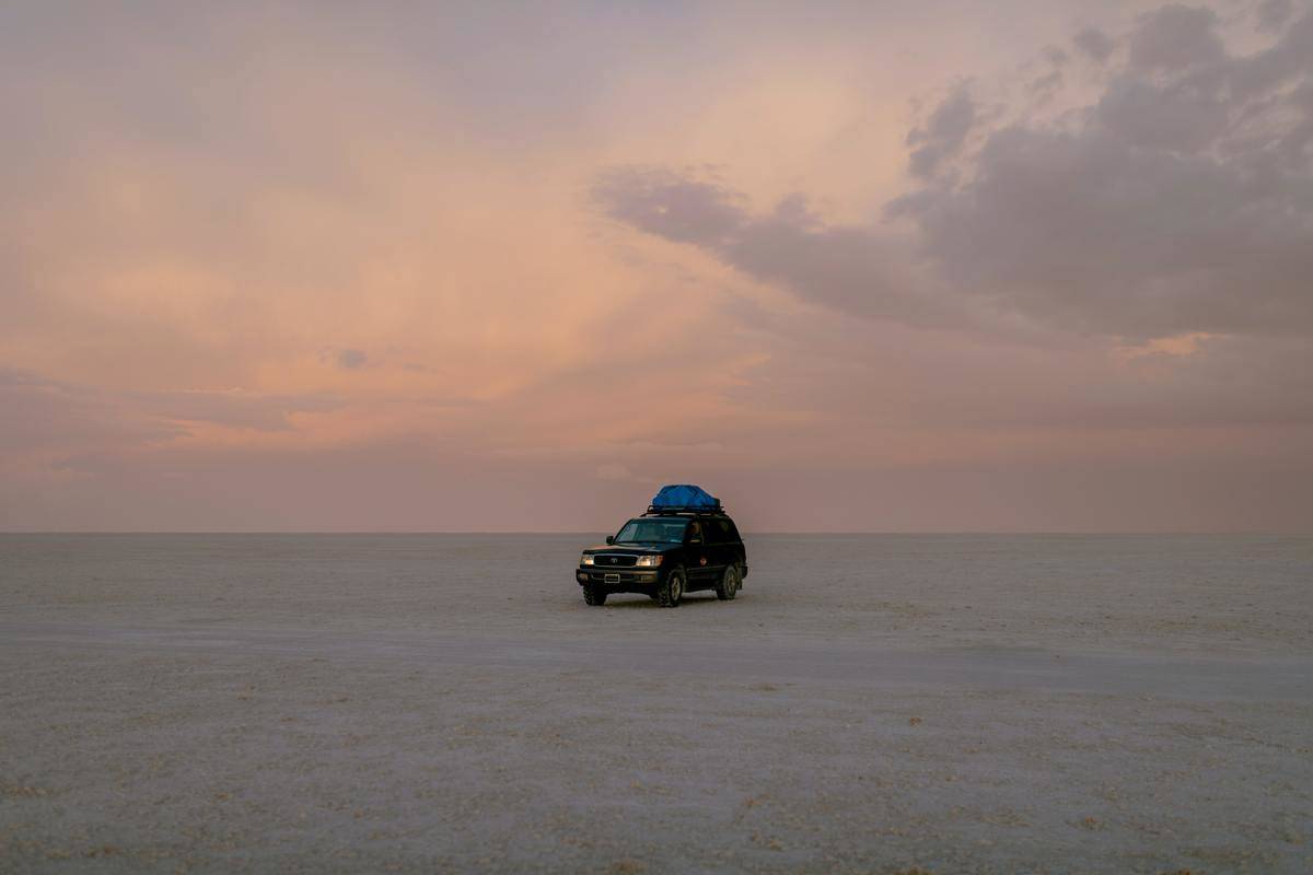 Car parked in desert at sunset