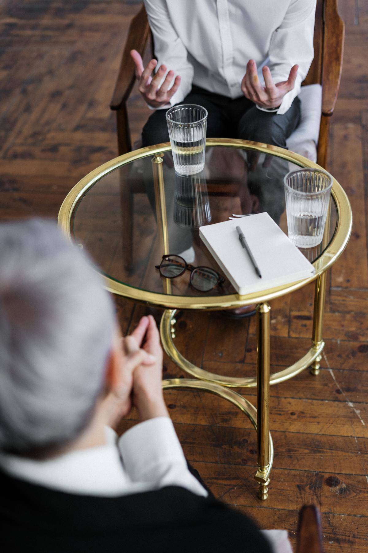 Two people having a conversation with glasses of water on a bistro table between them