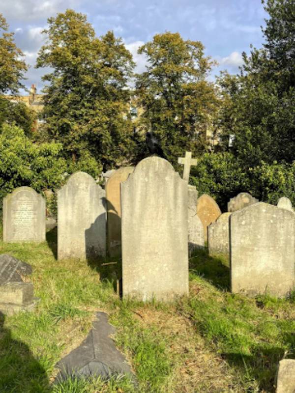 Cemetery tombstones and a bird is seen in the shadows.