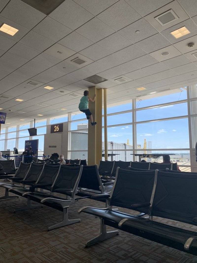 Child climbing support beam in airport 