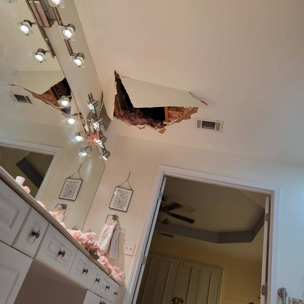 A hole in the ceiling over a bathroom where a person fell through and landed on the floor.