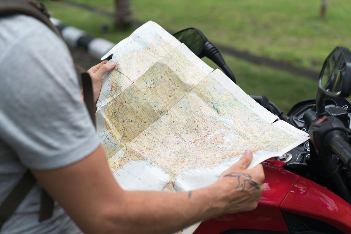 Man holding paper map while on motorcycle 