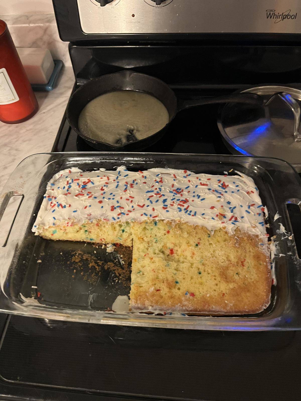 A partially eaten cake with most of the frosting licked off. 