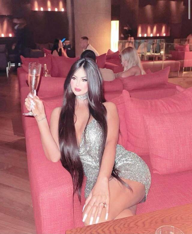 Woman holding a glass of champagne in a dress with a very small edited head.