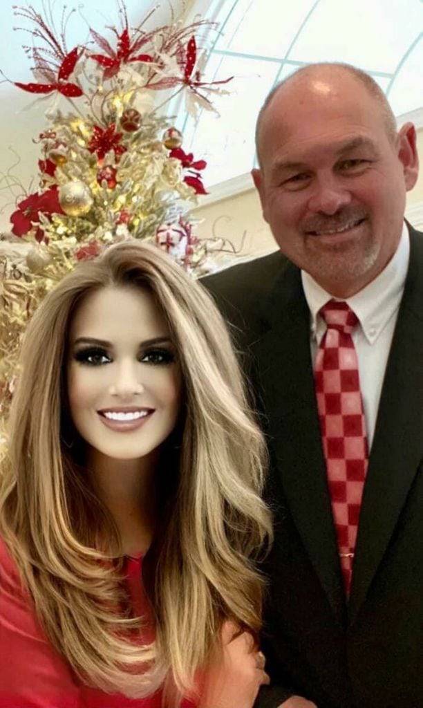 Heavily Photoshopped woman in a red dress standing with a bald man in a suit and red tie.