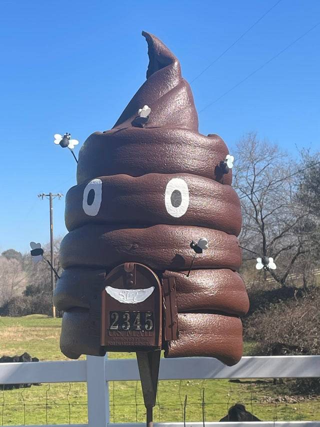 Mailbox on fence shaped like giant poop emoji