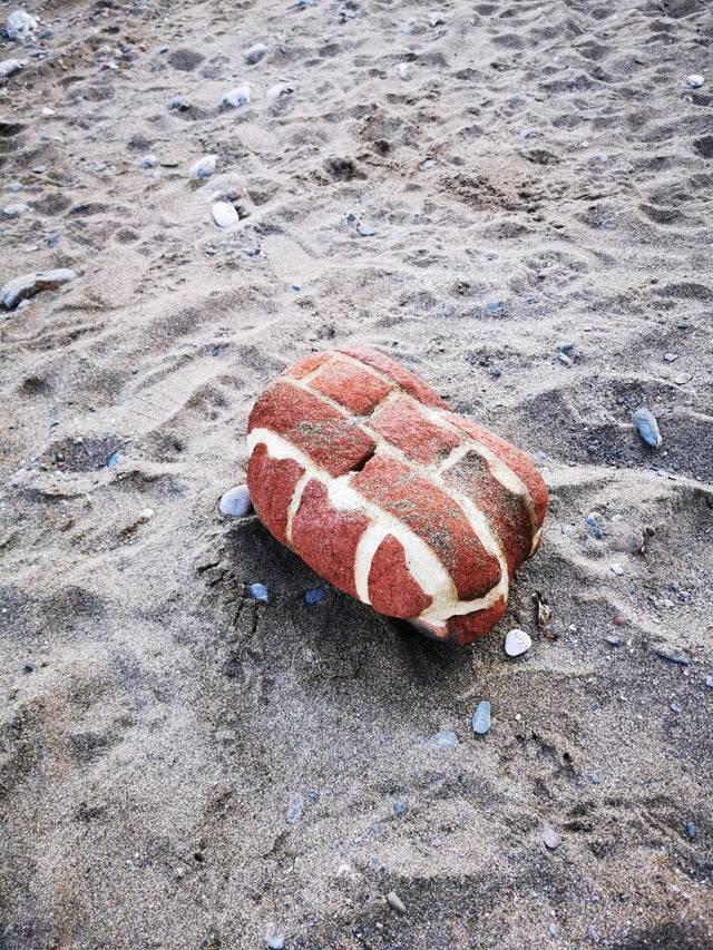 Clump of bricks on the beach that is rounded. 