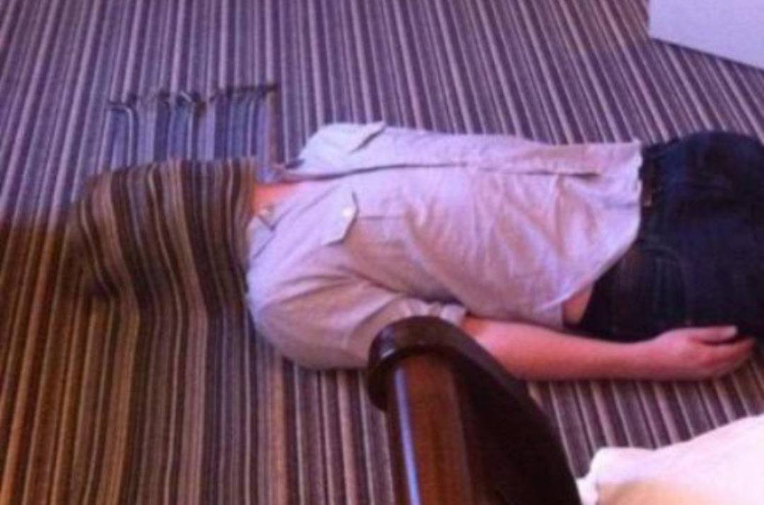 Person lying down on carpet with a scarf over their face that blends into the carpet.