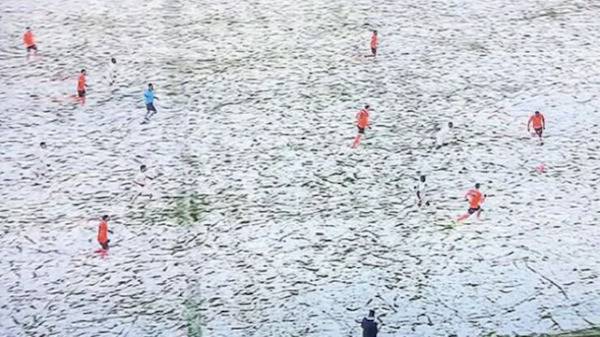 Soccer game in the snow with red and white player uniforms.