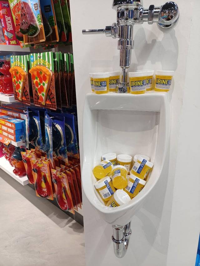 Candy packaged in urine sample cups and displayed in urinal in store
