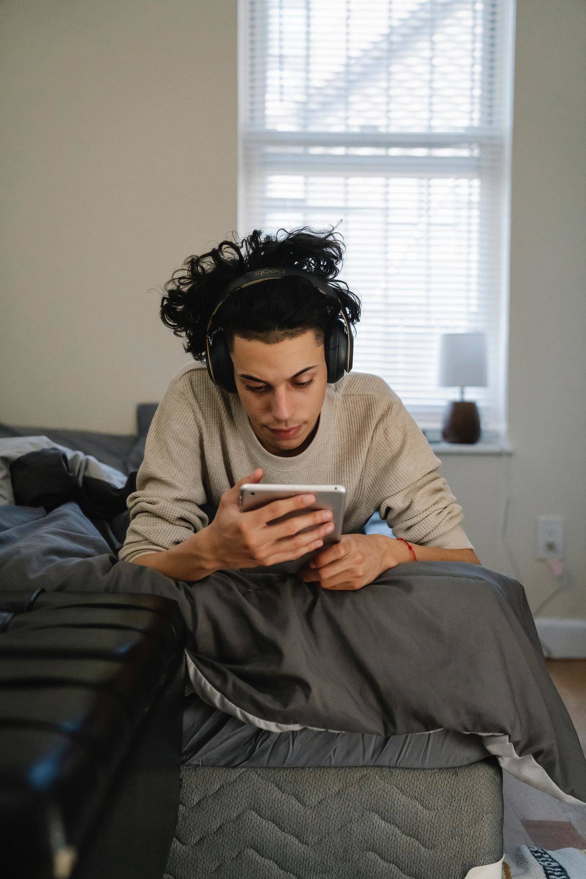 Teenager looks at phone while lying in bed 