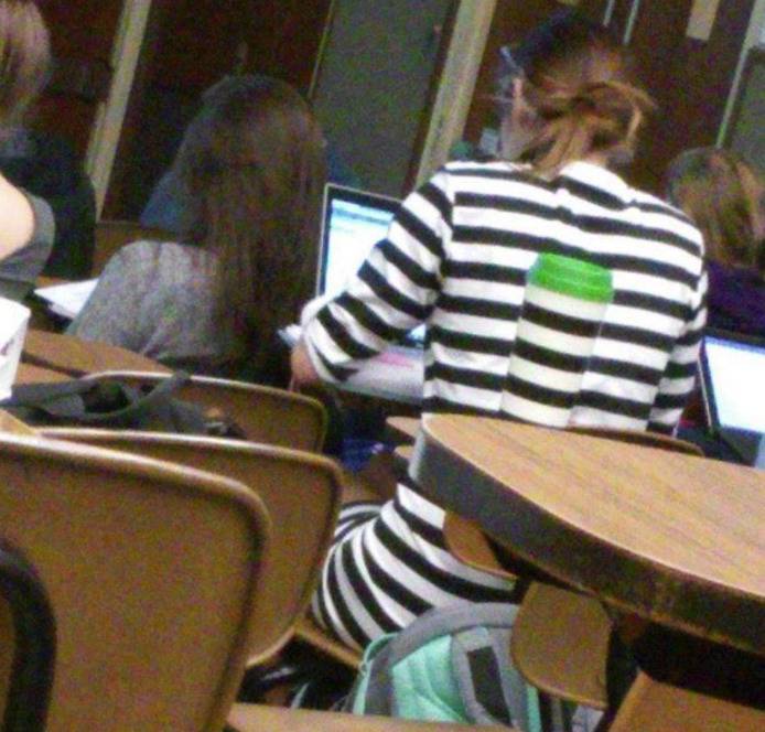 Woman in white and black striped shirt that blends in with the white and black water bottle.