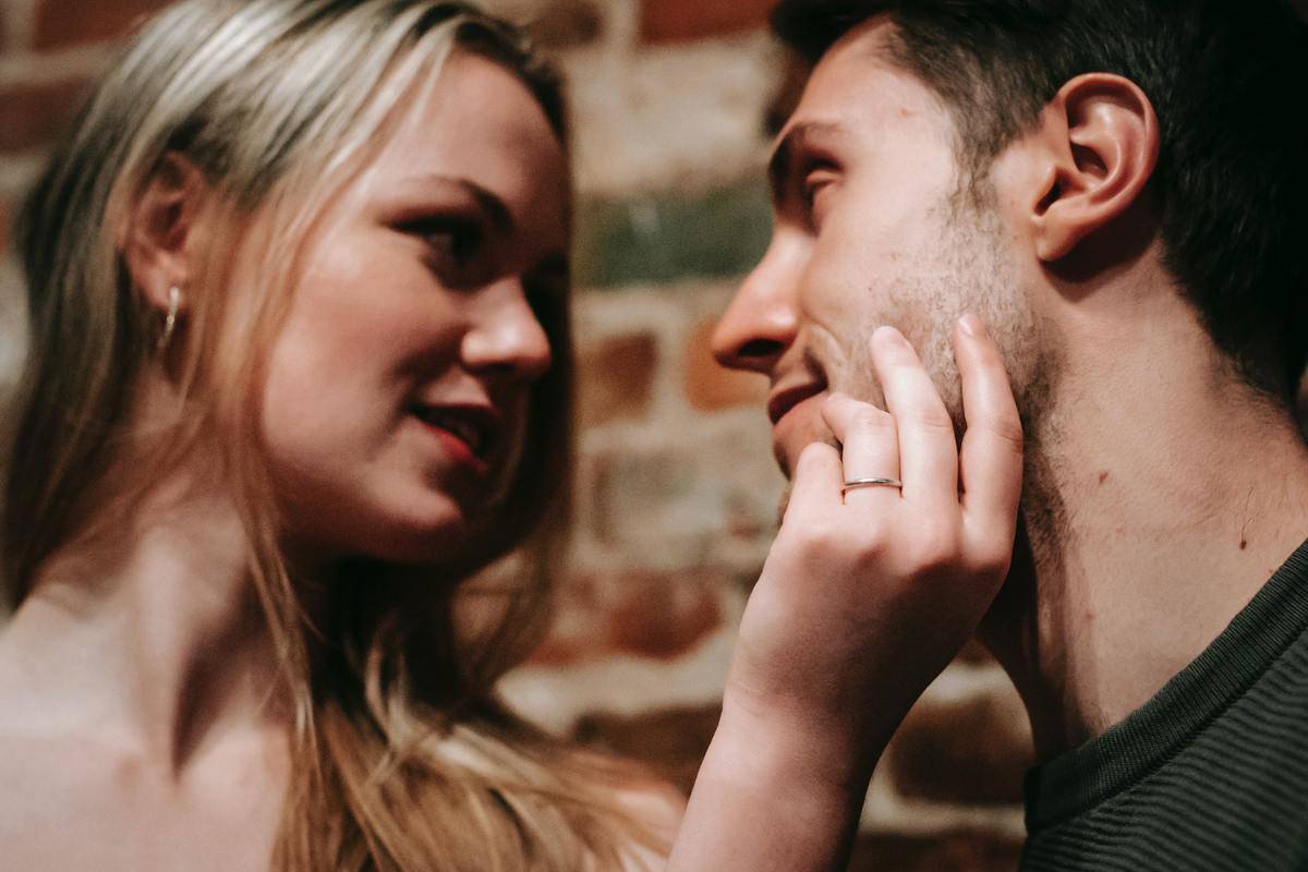 Woman holds man's face as they gaze into each other's eyes