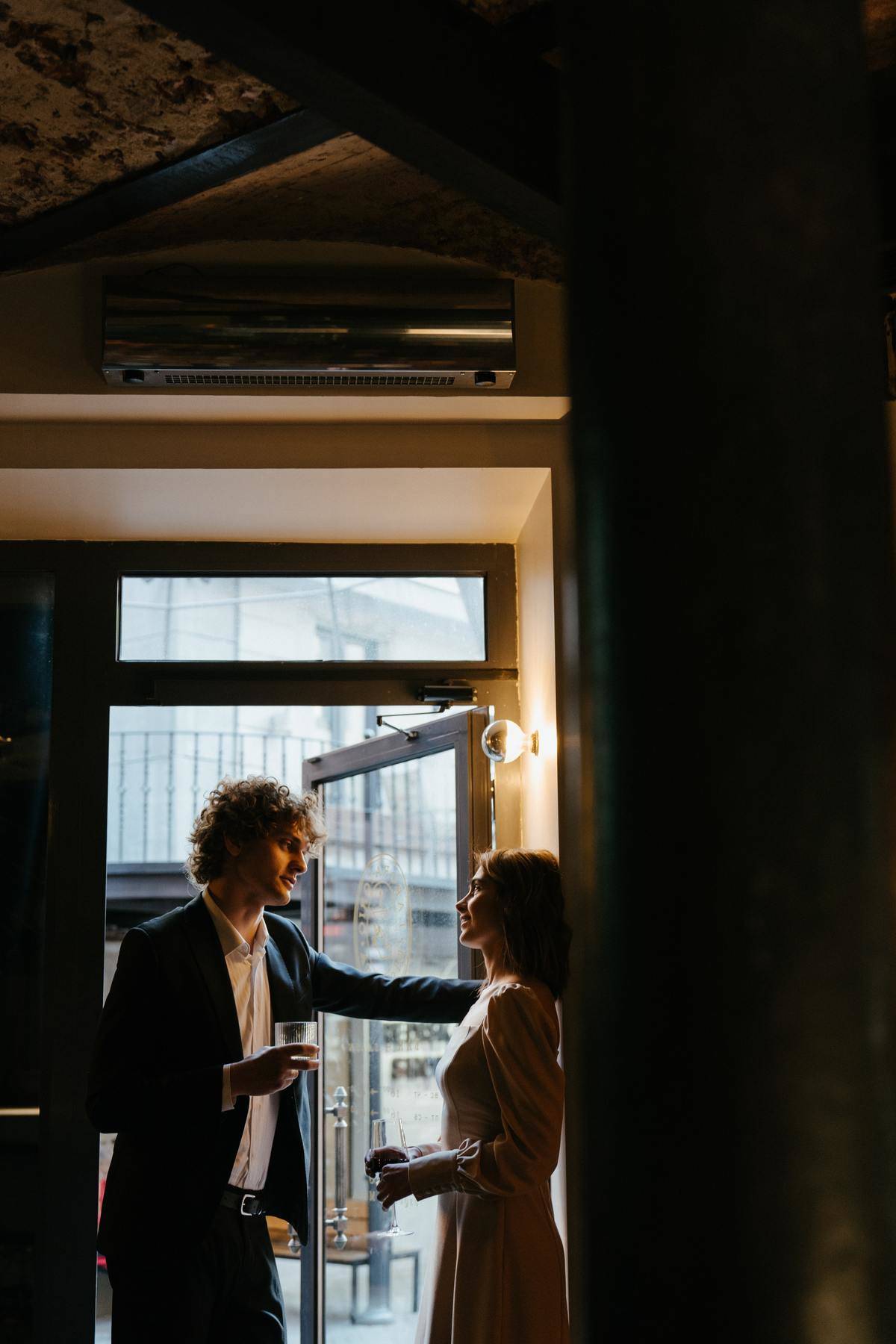Man leaning on door frame past woman 