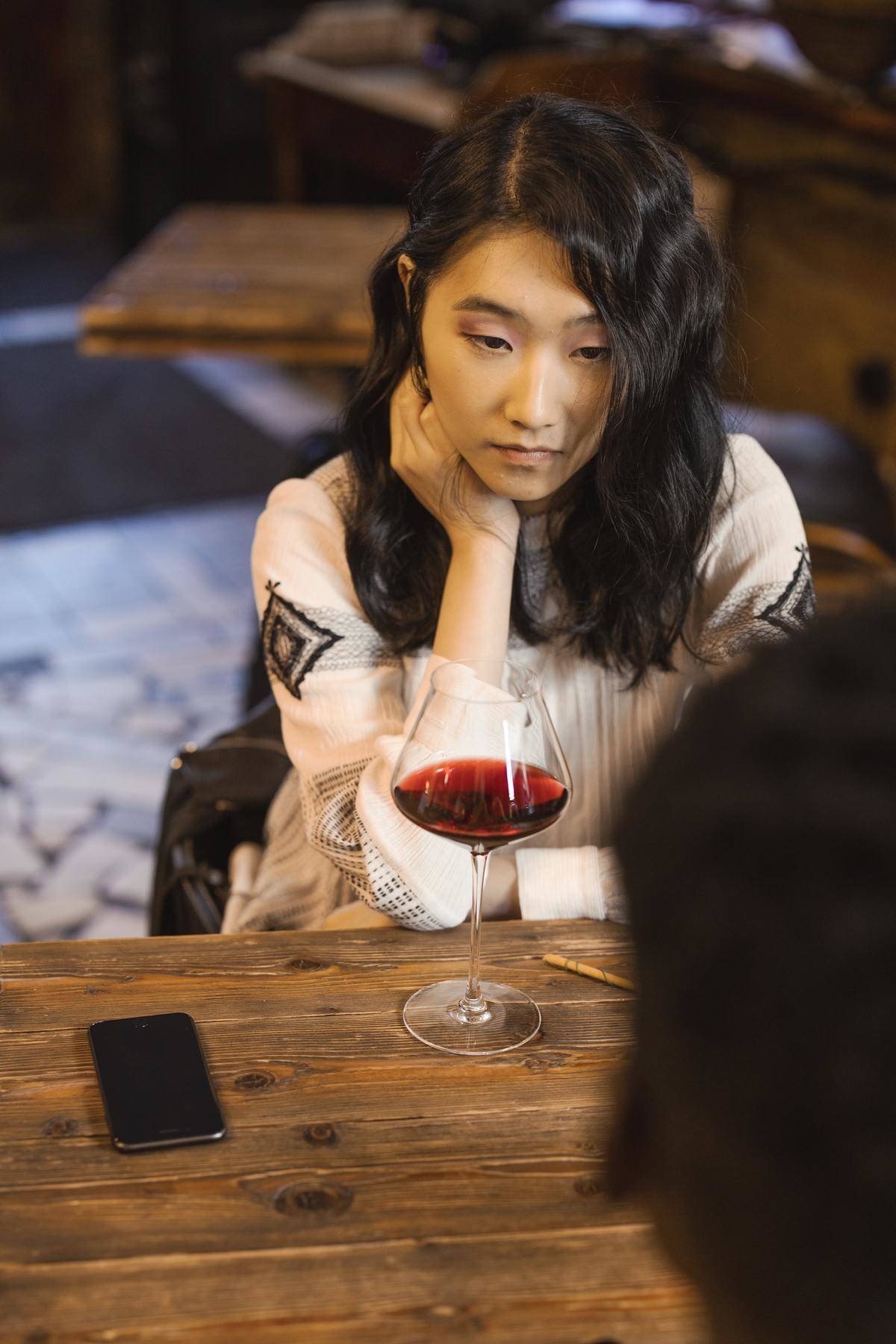 Woman looking at date over glass of wine