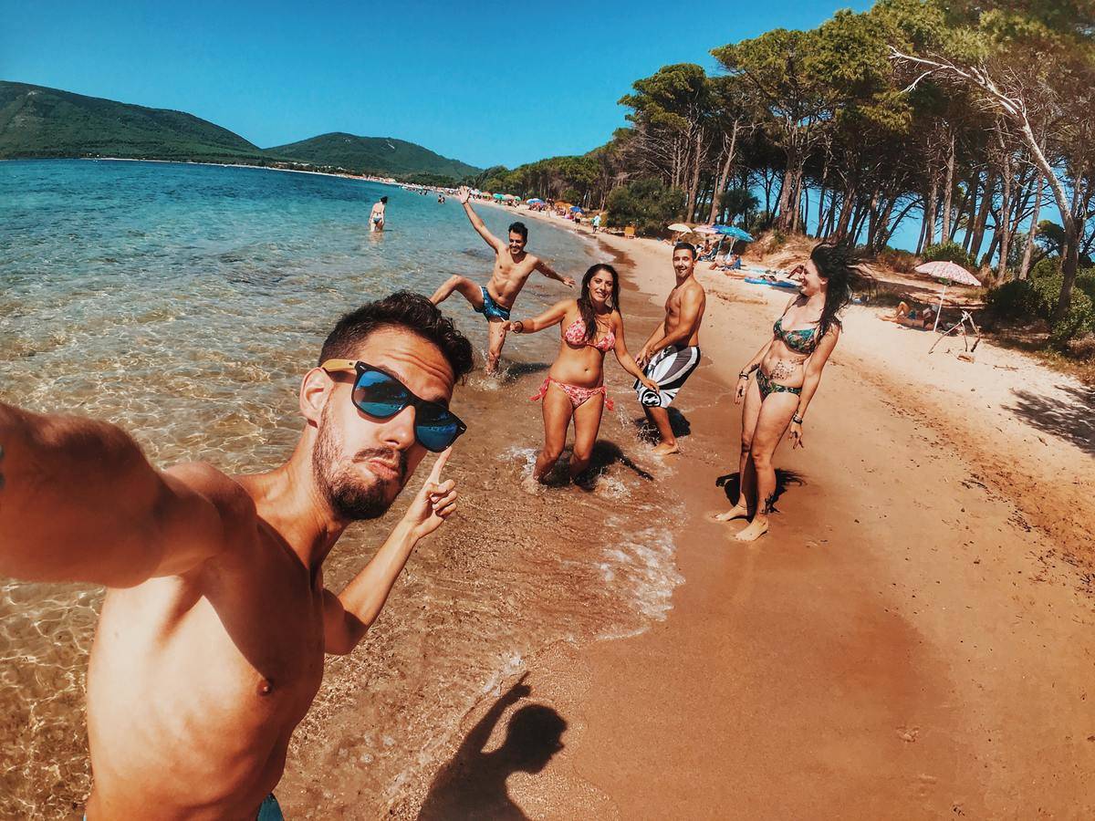 Man taking selfie at beach with group of friends