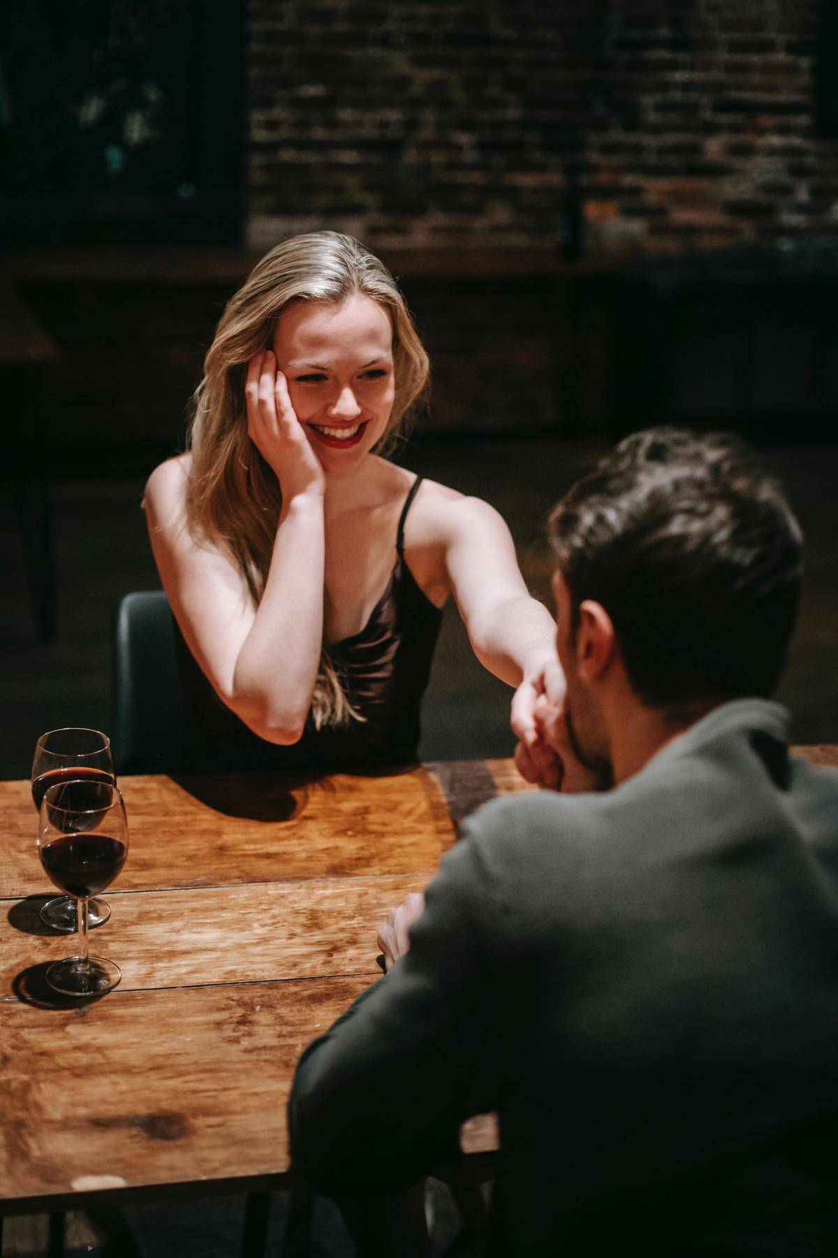 Man kissing woman's hand across table, she smiles bashfully